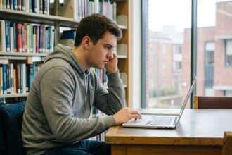 Étudiant en bibliothèque utilisant un ordinateur portable