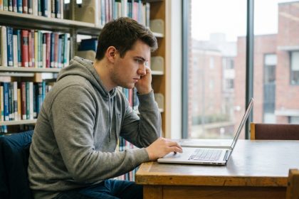Étudiant en bibliothèque utilisant un ordinateur portable